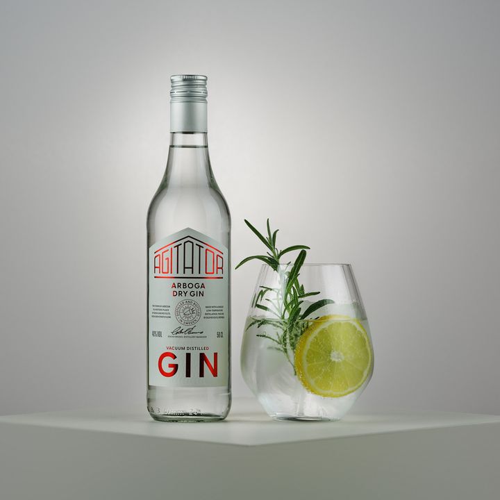 Flaska med Arboga Dry Gin bredvid ett glas gin och tonic med is, citrus och rosmarin.