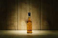 Flaska med rom på ett träbord, mot en träbakgrund.