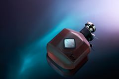 En elegant flaska med cognac ligger på en reflektiv yta med lila och blå belysning.