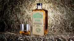 Flaska med whisky och ett glas whisky står på hö. Etiketten visar "AMATOR" och "ARGUMENT: ALL GRAINS".