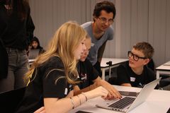 En grupp unga personer sitter vid en dator och diskuterar.