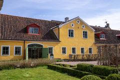 Bild av en gul byggnad med rött tak och gröna fönster och dörrar, kallad Allmogehallen på Kulturen i Lund.