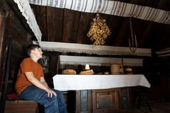 En pojke sitter vid ett bord i ett rum dekorerat med traditionella textilier och en handgjord takdekoration.