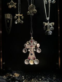 Alt text: Olika smycken av dräktsilver, inklusive striglakors, hänger mot en mörk bakgrund.