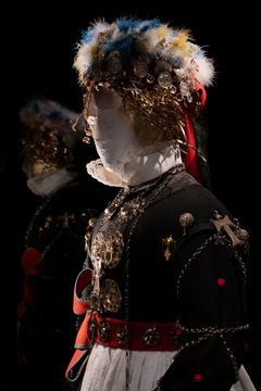 Docka med högtidskläder och huvudbonad översållade med dräktsilver.