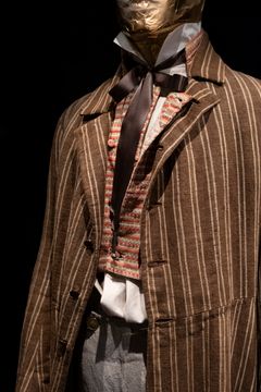 Alt text: Brunrandig livrock med väst samt skjorta som enligt rådande mode är synlig mellan väst och byxor.