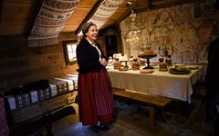 Kvinna klädd som en piga på 1800-talet står framför ett dukat bord i Blekingegården, ett av de historiska husen på Kulturen i Lund.