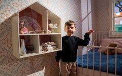 Ett barn från Holkens förskola i Lund leker inomhus vid en väggmonterad hylla och en liten säng.