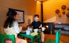 Två barn leker vid ett bord i ett kök i en lekutställning.