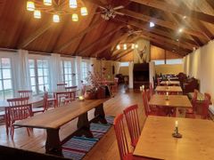 En lokal möblerad som ett café, med träbord och rödmålade stolar.