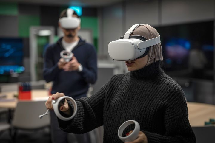 En person med VR-headset och kontroller i ett labb.