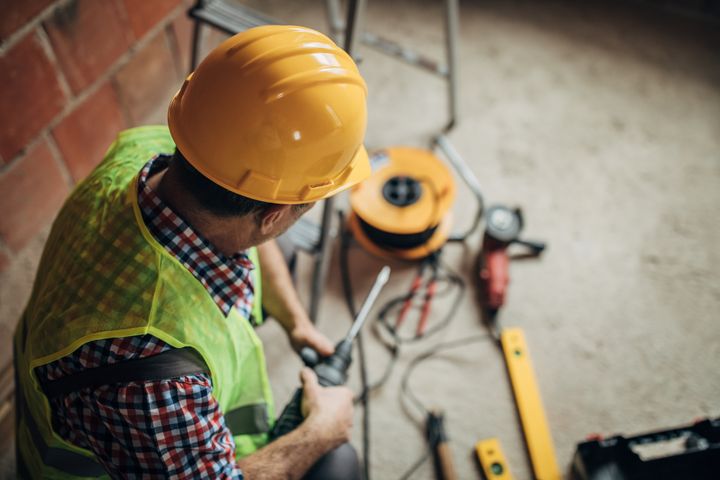 Arbetsklädd manlig elektriker med sladdvinda