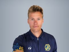 Porträtt av en man i en mörkblå sporttröja med logotyp.