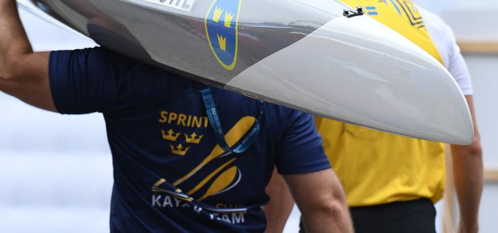 Person bär en kanot med svenska flaggan på.