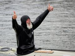 En person i våtdräkt sitter i en kajak och visar tummarna upp.