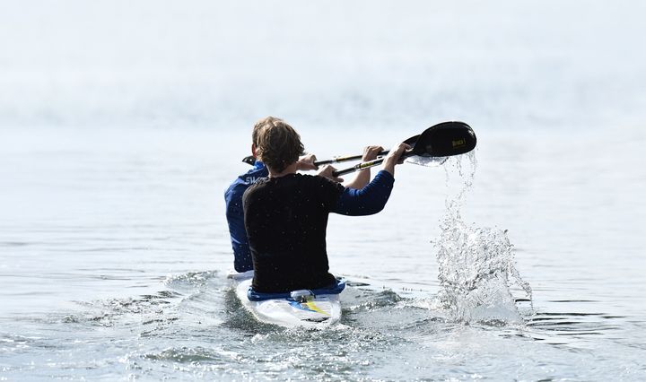 Person paddlar kajak på lugnt vatten.
