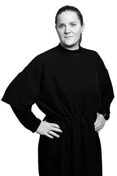 Fotografi av Emma Nilsson i svart klänning står med händerna i sidorna."