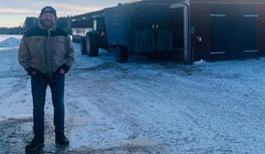 Tomas Andersson står på gårdsplanen utanför sin ladugård, det är snö på marken.