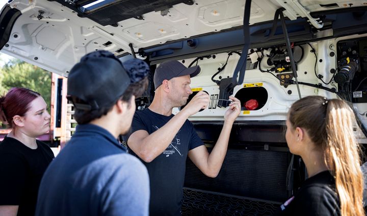 Fyra personer studerar motorutrymmet på ett fordon.