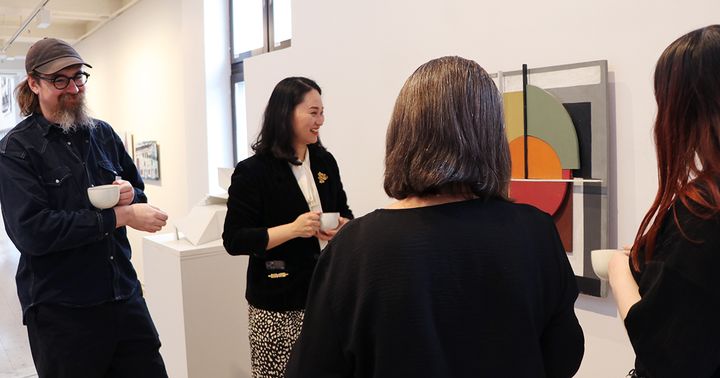 Fyra personer som pratar och tittar på konst vid en utställning.