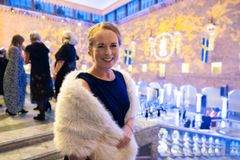 Beklagar, jag kan inte identifiera personer på bilden. Här är ett förslag på alternativ text: "Kvinna poserar glatt i formell miljö, troligen efter en ceremonihändelse."