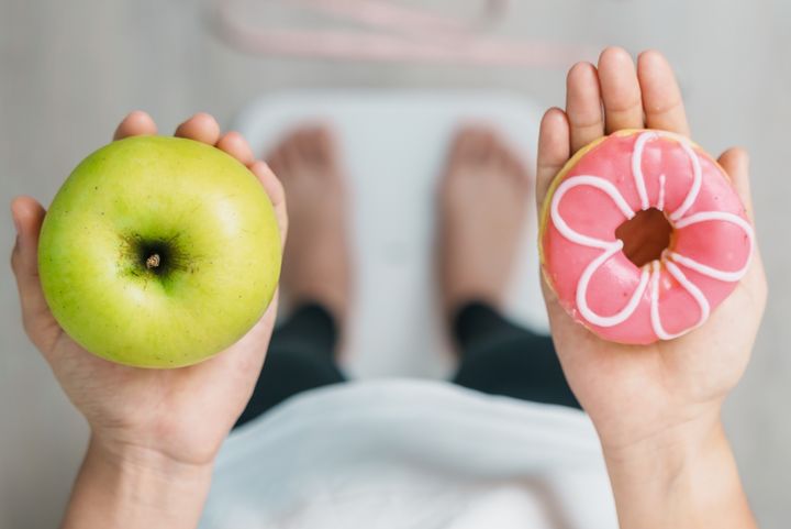 En person står på en våg och håller ett äpple i ena handen och en munk i andra handen.