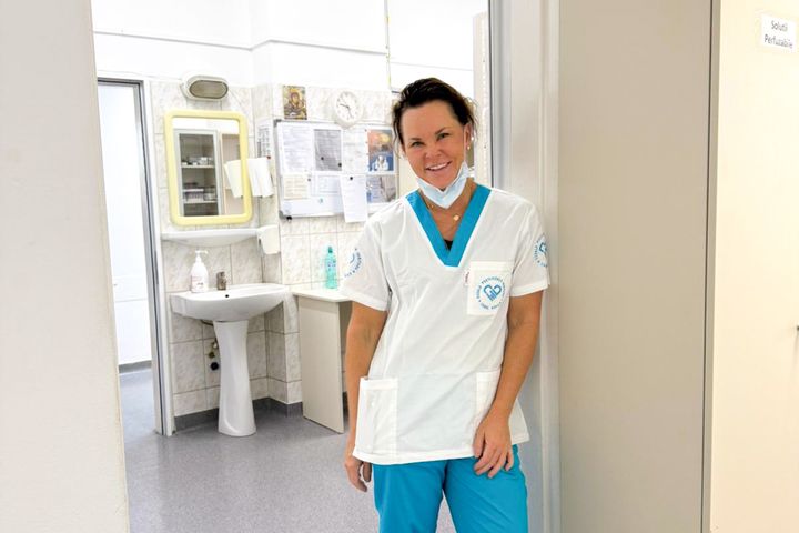 Sjuksköterskestudent i sjukhuskorridor, leende i vit arbetsklädsel.