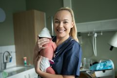 Kvinna i sjukhuskläder håller ett nyfött barn på ett sjukhus.
