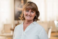 Alt text: Porträtt av en leende kvinna i ljus skjorta.