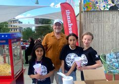 Tre ungdomar i svarta t-shirts med texten Tigrarna och en vuxen bjuder på popcorn.