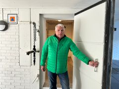 En man i grön jacka håller upp dörren till ett skyddsrum