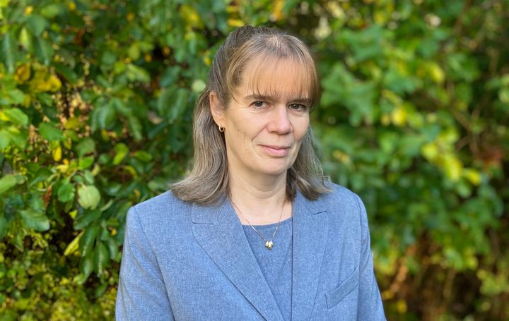 Porträtt på kvinna med grönskande bakgrund.