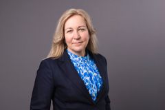 En blond kvinna i svart kavaj och blåmönstrad blus.