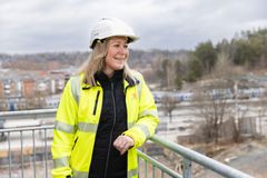 En blond kvinna i varseljacka och bygghjälm