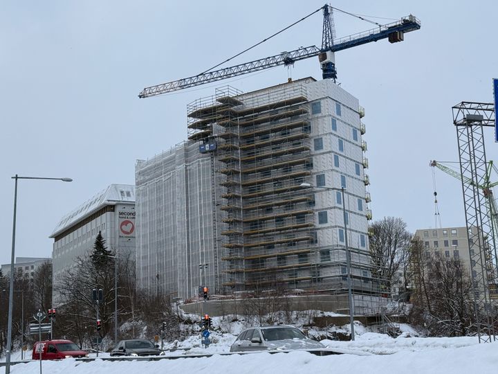Bygget av ett flerbostadshus. I bakgrunden syns en byggkran.