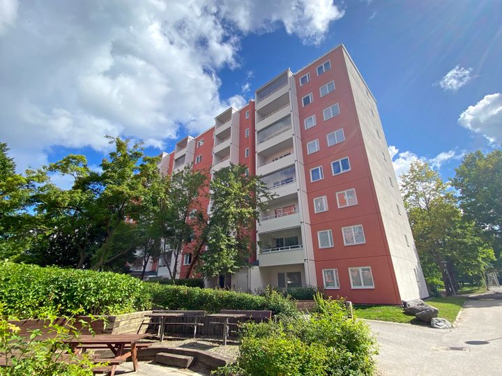 Ett rött flervåningshus mot en blå himmel.