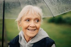 glad äldre kvinna under ett paraply