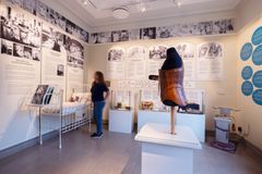 Utställningsrum med historiska medicinska föremål och informationstavlor på väggarna. En suddig person går förbi utställningen.