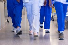 Personer i vårdkläder går i en sjukhuskorridor.