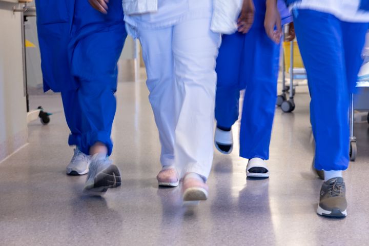 Personer i vårdkläder går i en sjukhuskorridor.