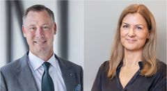 Två personer, en man och en kvinna, i formella kläder står och ler mot kameran.