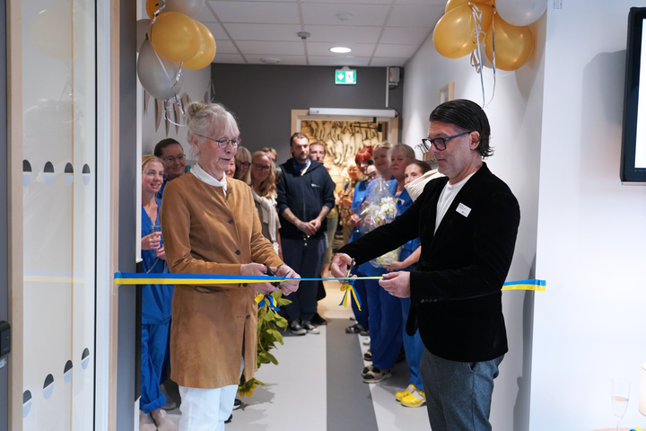 En%20kvinna%20och%20en%20man%20st%E5r%20bredvid%20varandra%2C%20b%E5da%20h%E5ller%20i%20varsin%20sax%2C%20de%20klipper%20gemensamt%20ett%20randigt%20band%20i%20f%E4rgerna%20gul%20och%20bl%E5.%20De%20b%E5da%20ler%20och%20ser%20glada%20ut.