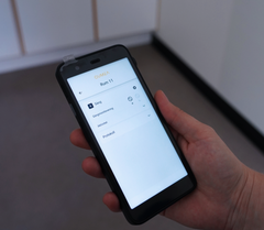 En hand håller i en mobiltelefon som lyser upp.