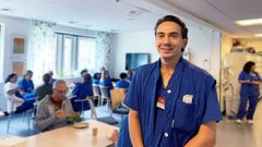 En läkare i blå sjukhuskläder står i ett personalrum