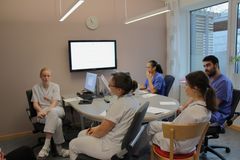 Läkar-och sjuksköterskestudenter som sitter vid ett bord och diskuterar.