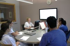 Läkar- och sjuksköterskestudenter som sitter vid ett bord och diskuterar.