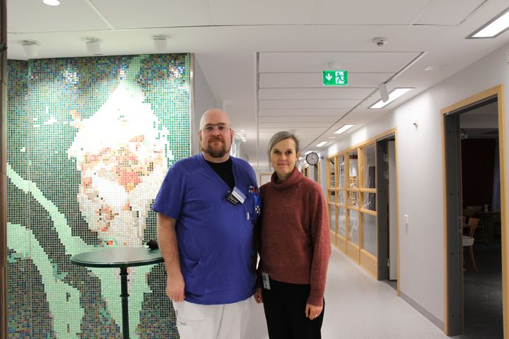 Två personer som står i sjukhusmiljö och ler mot kameran.