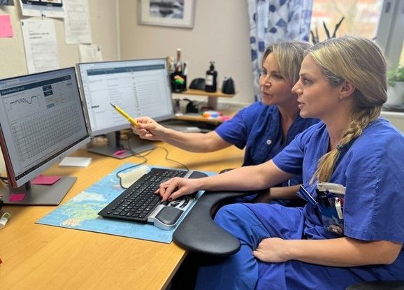 Två sjuksköterskor sitter framför datorn och pekar mot skärmen.