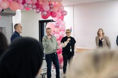 Medarbetare håller tal framför säntvätten med rosa ballonger i bakgrunden.