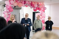 Medarbetare håller tal framför sängtvätten med rosa ballonger i bakgrunden.
